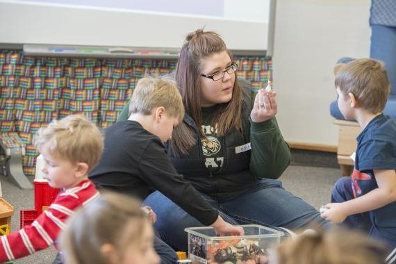 A student teacher showing young students a figure in a classroom